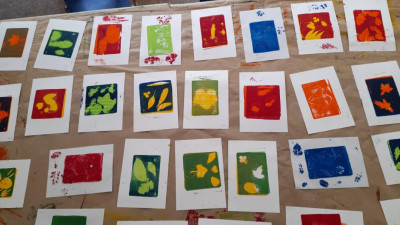 Auf einem Tisch liegen viele verschiedene Druckerzeugnisse eines Workshops. Die Drucke sind sehr unterschiedlich bunt.