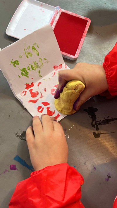 Kinderhände stempeln ein Blatt Papier mit einem selbstgemachten Stempel.