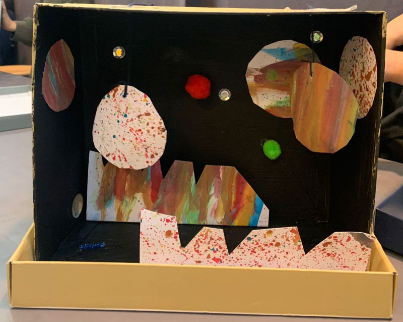 text: >
  Diorama eines bunten Universums in einem
  Schuhkarton mit bemalten Planeten,
  Sternen und einer Landschaft aus
  Wellpappe
decorative: false
source: reviewed