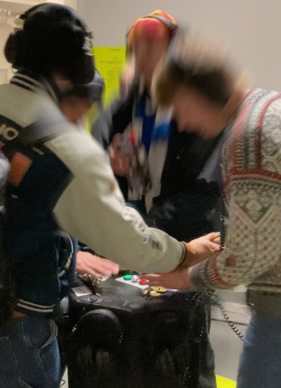 Mehrere Personen bedienen gemeinsam eine interaktive Installation mit Knöpfen und Schaltern