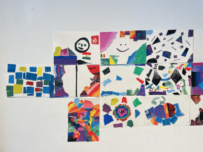 Bunte Collage-Kunstwerke von Kindern zum Thema Emotionen an einer weißen Wand