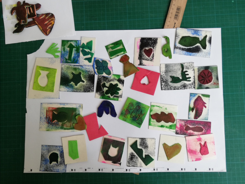 text: >
  Viele kleine, farbige Drucke und
  ausgeschnittene Formen – darunter
  Herzen, Fische, Hände, Pfeile und
  Blumen – liegen auf einem weißen
  Blatt auf einer grünen Schneidematte;
  oben rechts ist ein Holzlineal zu sehen.
decorative: false
source: manual