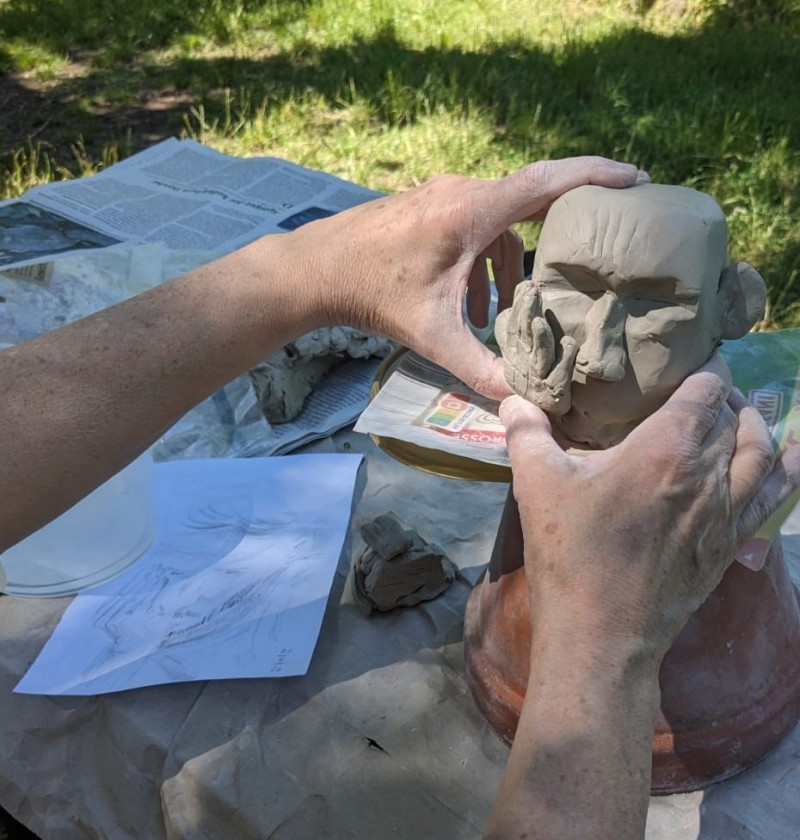 text: >
  Künstler arbeitet an einer
  Keramik-Skulptur, die eine menschliche
  Kopfform zeigt, während er mit Skizzen
  und Materialien an einem
  Outdoor-Arbeitsplatz sitzt
decorative: false
source: reviewed