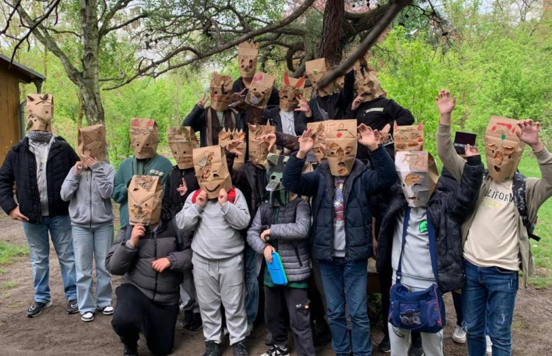 text: >
  Gruppe von Kindern mit selbstgebastelten
  Papiermasken verschiedener Gesichter
  unter einem Baum
decorative: false
source: reviewed