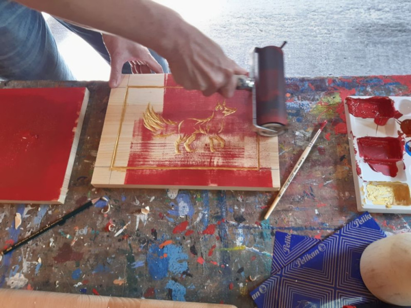 text: >
  Eine Holzplatte, in die ein Fuchs als
  Bild reingeschnitzt wurde und die gerade
  mit einer Walze rot gefärbt wird.
decorative: false
source: manual