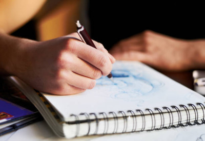 „Hand zeichnet mit einem Stift in einem Skizzenbuch.“