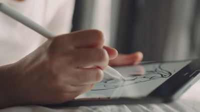 „Person zeichnet mit einem Stift auf einem Tablet.“