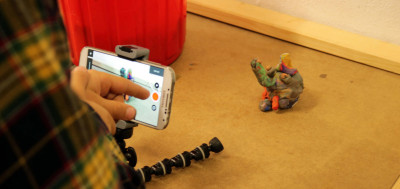 „Person filmt eine selbstgemachte Figur aus Knetmasse mit einem Smartphone.“